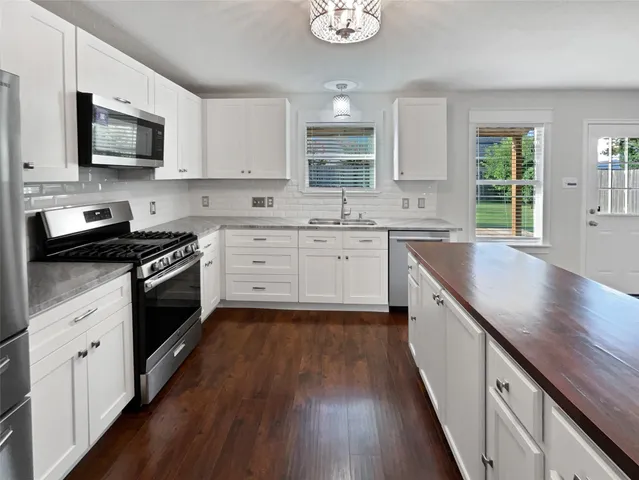 a kitchen with granite countertop stainless steel appliances a sink cabinets and wooden floor