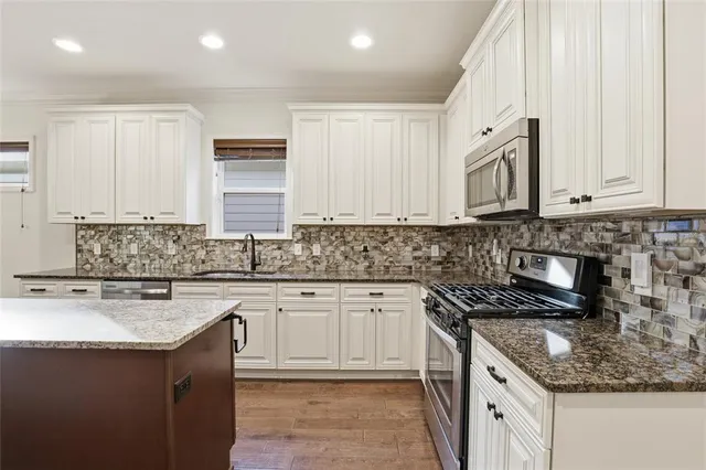 a kitchen with stainless steel appliances granite countertop a sink a stove and a refrigerator