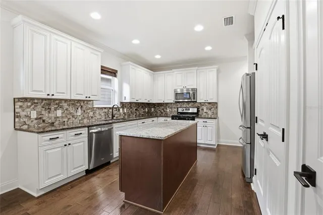 a view of an empty room with wooden floor and a ceiling fan