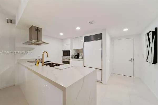 a kitchen that has a sink a refrigerator and a stove top oven