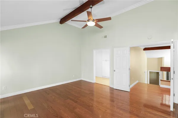 an empty room with wooden floor fan and windows