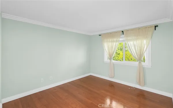 a view of an empty room with wooden floor and window