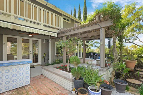 a view of a patio with table and chairs potted plants and floor to ceiling window and potted plants