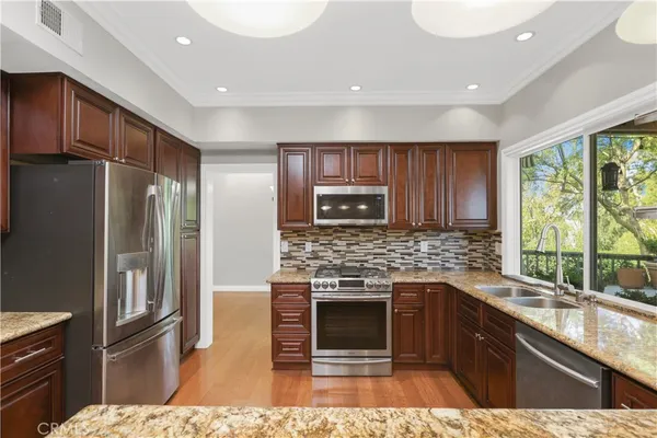 a kitchen with stainless steel appliances kitchen island granite countertop a refrigerator and a sink