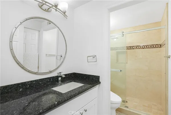 a bathroom with a granite countertop sink a mirror and a shower