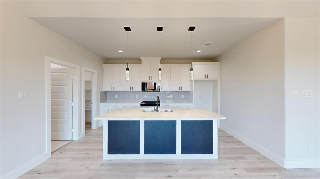 801 Birch Street Grand Prairie, TX 75050 - Photo 3 of 28 a large white kitchen with kitchen island a sink stainless steel appliances and cabinets