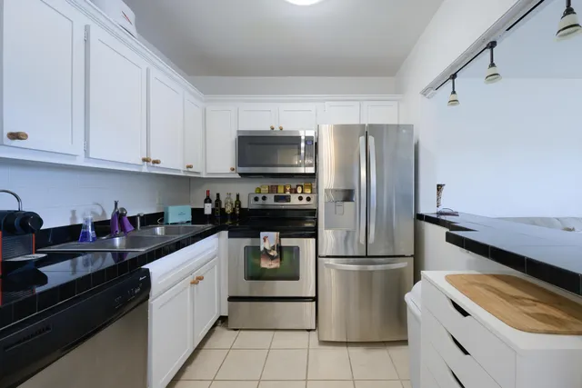 a kitchen with granite countertop a refrigerator stove and sink