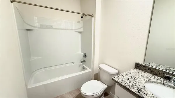 a bathroom with a granite countertop sink and a toilet