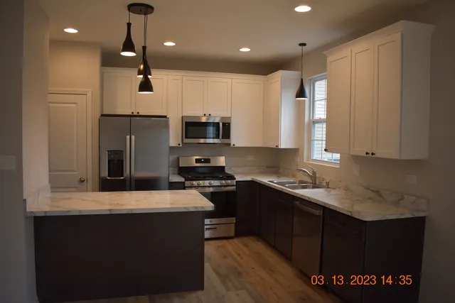 a kitchen with kitchen island granite countertop a sink a counter top space stainless steel appliances and cabinets