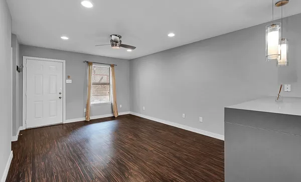 a view of an empty room with wooden floor and a window