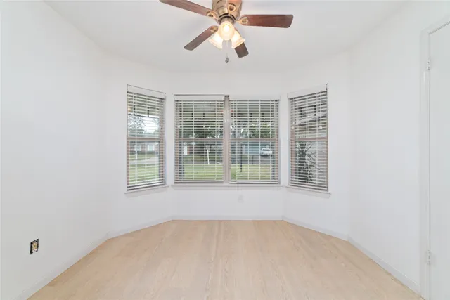 an empty room with chandelier fan and windows