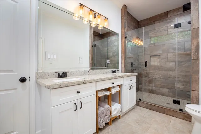 a bathroom with a granite countertop sink a mirror and a shower
