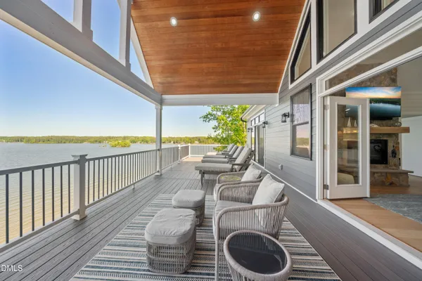 a view of a chairs and table on wooden deck with lake view