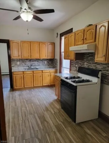 a kitchen with granite countertop a stove and a wooden floors