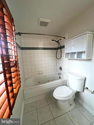 a bathroom with a granite countertop bathtub shower sink vanity and toilet