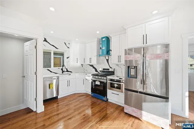 a kitchen with stainless steel appliances granite countertop a refrigerator a stove and a sink