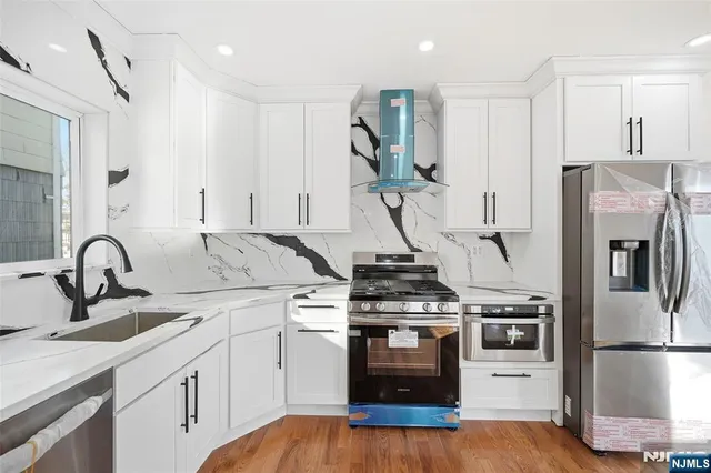 a kitchen with a sink stainless steel appliances and wooden floor