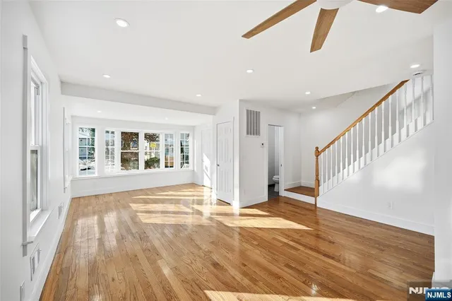 a view of an empty room with wooden floor and stairs