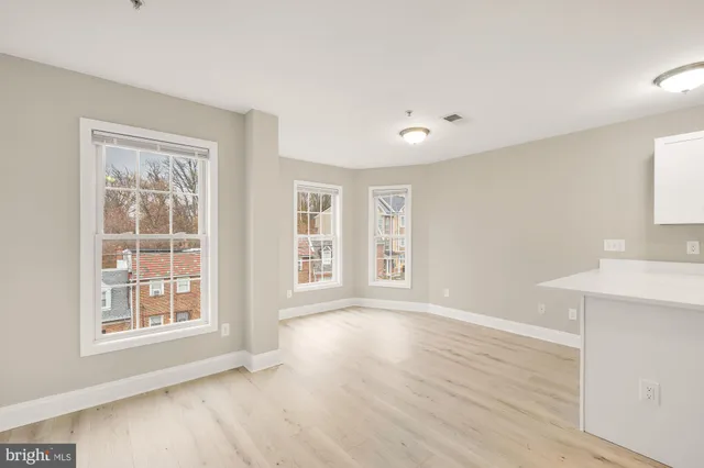 a view of an empty room with a window and wooden floor