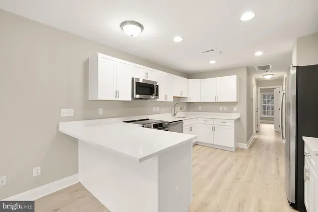 a kitchen with a sink a counter top space stainless steel appliances and cabinets