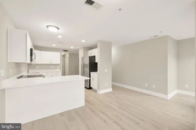 a large white kitchen with a refrigerator a stove top oven a counter space and wooden floor