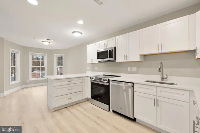 a kitchen with granite countertop white cabinets and stainless steel appliances