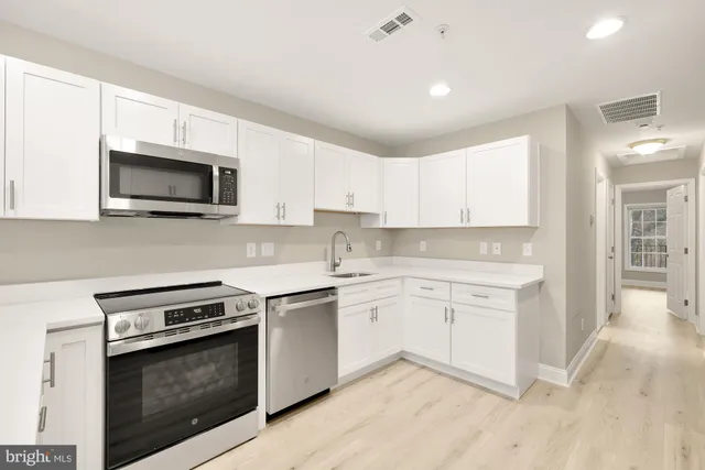 a kitchen with granite countertop white cabinets sink and stainless steel appliances