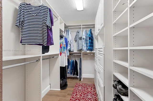 a view of walk in closet with clothes and shoes