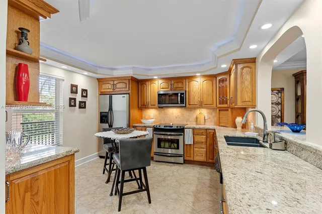 a view of a kitchen with kitchen island a large window a sink and stainless steel appliances