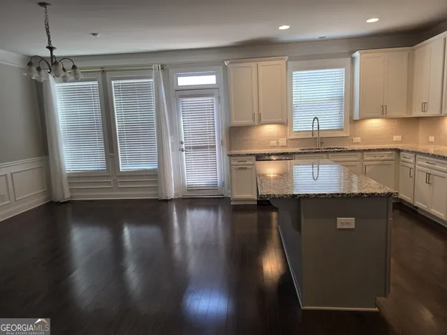 a kitchen with granite countertop a stove a sink and a granite counter tops with wooden floors