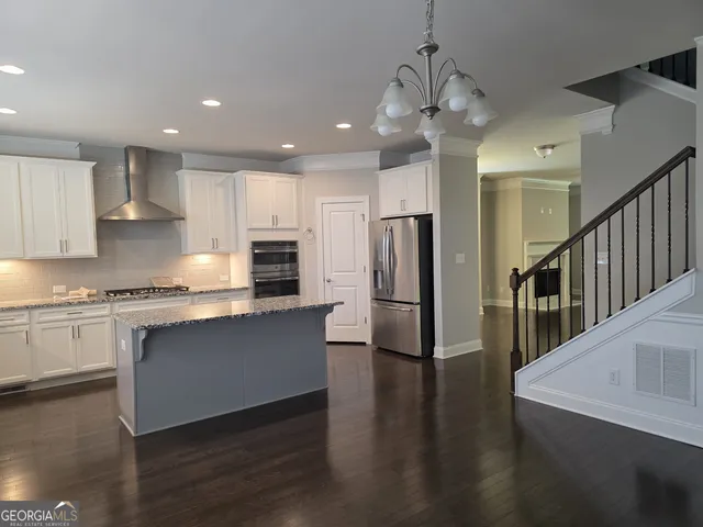 a kitchen with stainless steel appliances granite countertop a refrigerator a sink dishwasher a stove and white cabinets with wooden floor