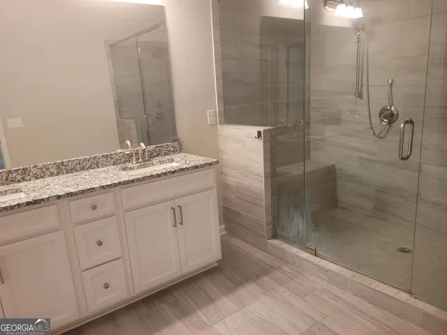 a bathroom with a granite countertop sink a mirror and a shower