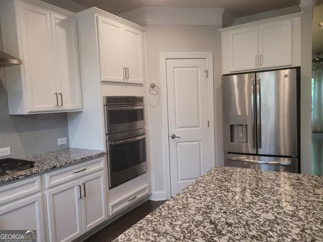 a kitchen with granite countertop white cabinets and stainless steel appliances