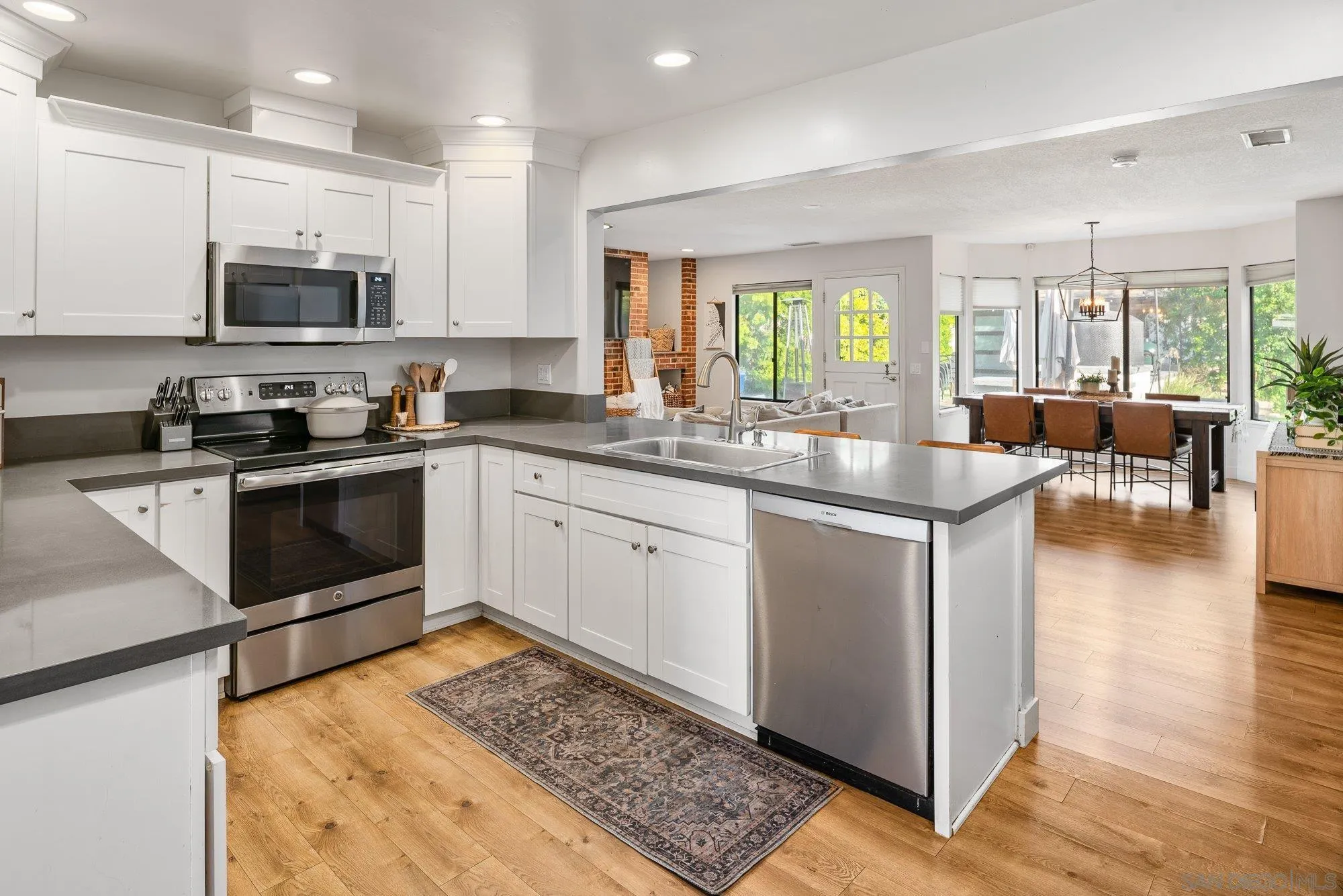 3491 Shawnee Road San Diego, CA 92117 - Photo 13 of 66 a kitchen with stainless steel appliances granite countertop a sink stove oven and white cabinets with wooden floor