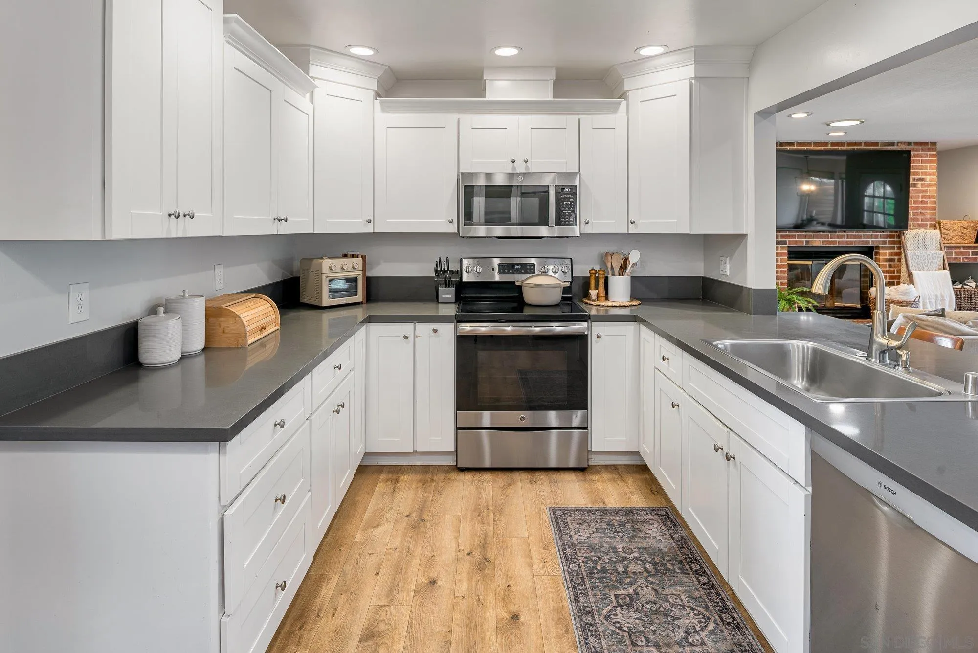 3491 Shawnee Road San Diego, CA 92117 - Photo 14 of 66 a kitchen with stainless steel appliances granite countertop a sink and white cabinets
