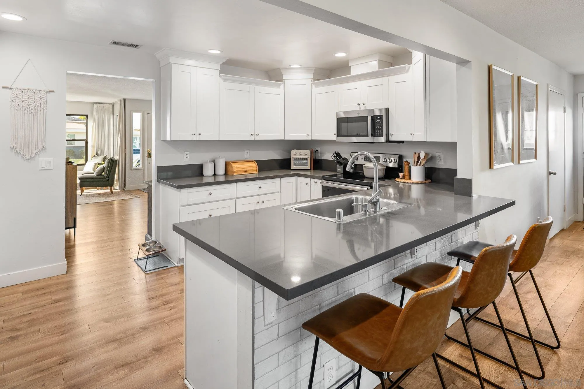 3491 Shawnee Road San Diego, CA 92117 - Photo 17 of 66 a kitchen with stainless steel appliances granite countertop a stove top oven a sink dishwasher and white cabinets with wooden floor