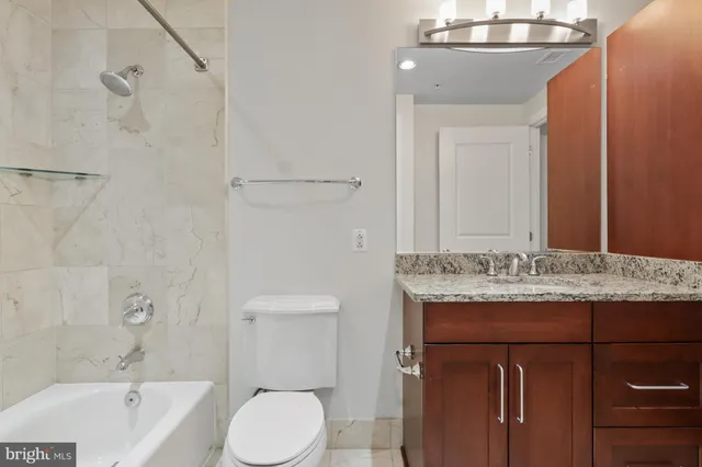 a bathroom with a granite countertop sink toilet and shower