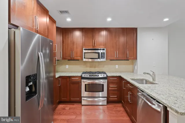 a kitchen with stainless steel appliances granite countertop a stove a refrigerator and a sink