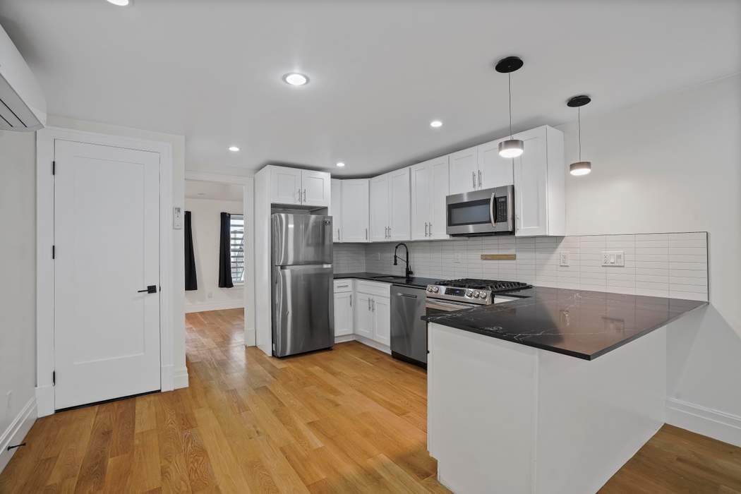 682 Madison Street Brooklyn, NY 11221 - Photo 19 of 28 a kitchen with stainless steel appliances granite countertop a refrigerator a stove top oven a sink and dishwasher with wooden floor