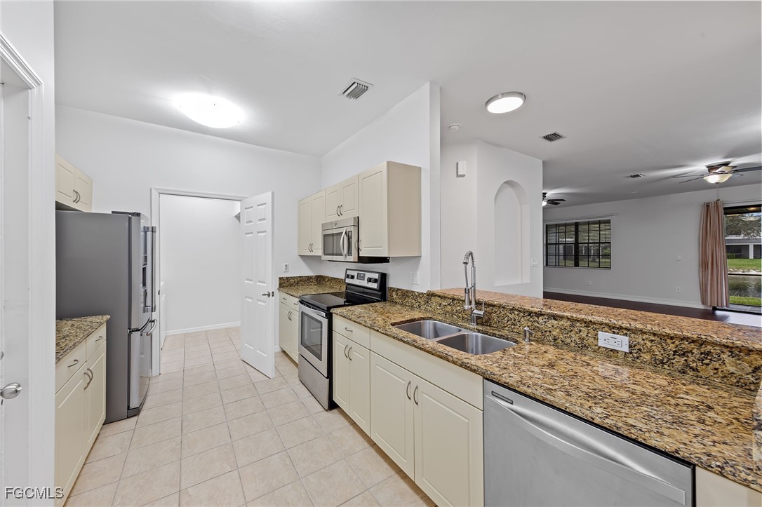 14764 Pinnacle Place, Unit 65 Naples, FL 34119 - Photo 16 of 50 a kitchen with stainless steel appliances granite countertop a sink stove and refrigerator