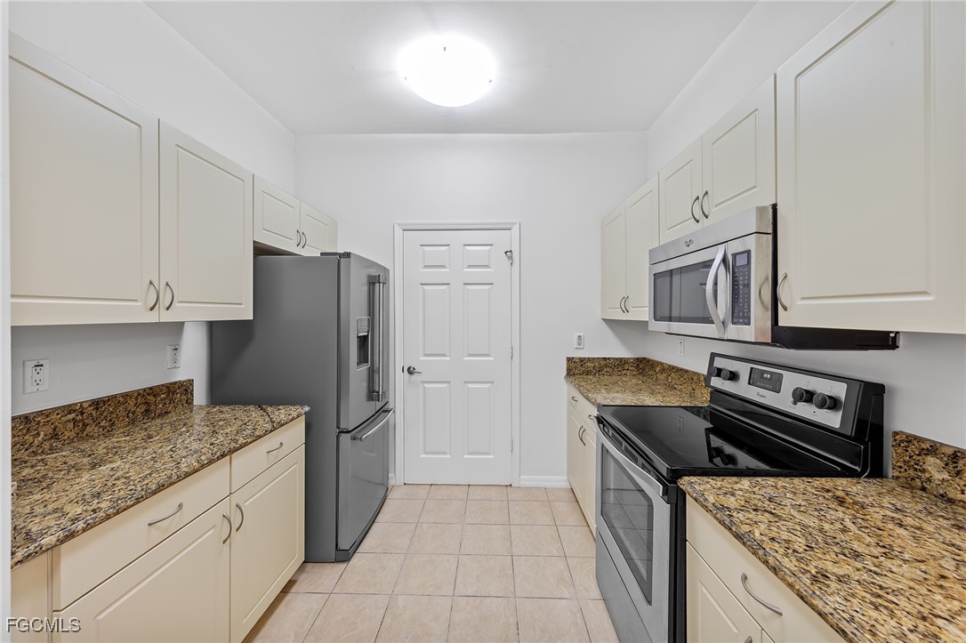 14764 Pinnacle Place, Unit 65 Naples, FL 34119 - Photo 18 of 50 a kitchen with stainless steel appliances granite countertop a refrigerator and a stove top oven