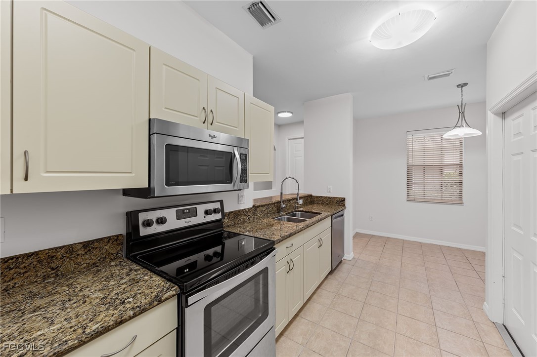 14764 Pinnacle Place, Unit 65 Naples, FL 34119 - Photo 19 of 50 a kitchen with stainless steel appliances granite countertop a stove and a microwave with white cabinets