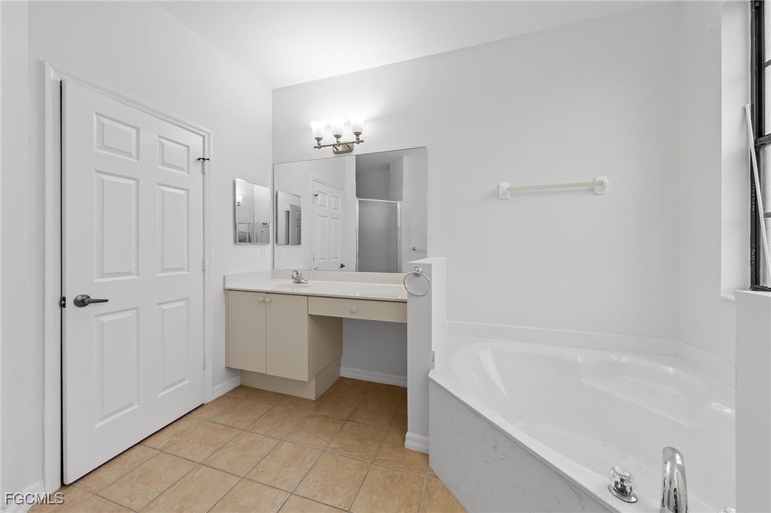 14764 Pinnacle Place, Unit 65 Naples, FL 34119 - Photo 30 of 50 a bathroom with a tub sink and mirror