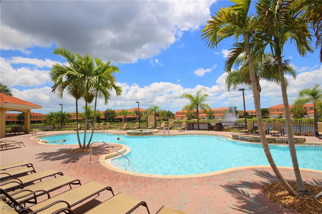 14764 Pinnacle Place, Unit 65 Naples, FL 34119 - Photo 44 of 50 a view of a swimming pool with a lounge chair and palm trees