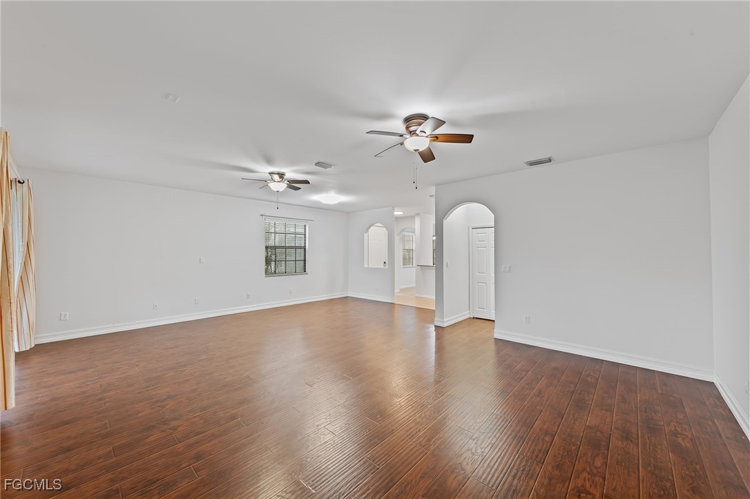 14764 Pinnacle Place, Unit 65 Naples, FL 34119 - Photo 9 of 50 an empty room with wooden floor chandelier fan and windows
