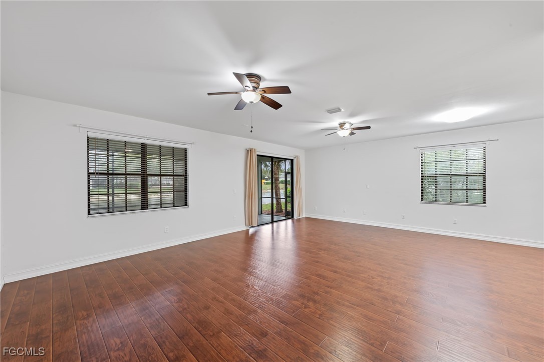 14764 Pinnacle Place, Unit 65 Naples, FL 34119 - Photo 10 of 50 a view of an empty room with chandelier fan and wooden floor
