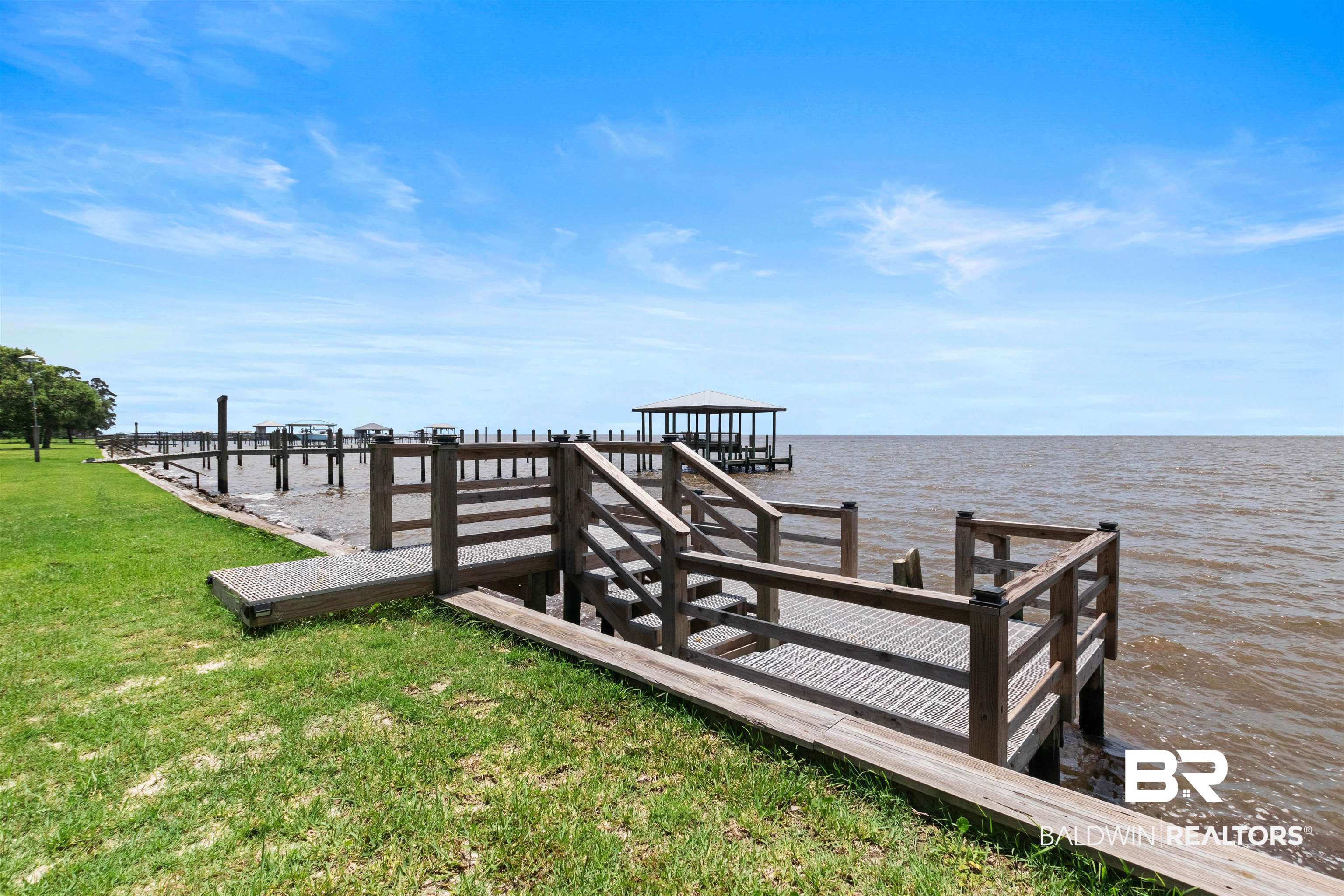 9581 South Bay Street Foley, AL 36535 - Photo 35 of 44 Waterfront property featuring a wooden dock with stairs and railing, a covered pier structure, and additional dock pilings extending into the water