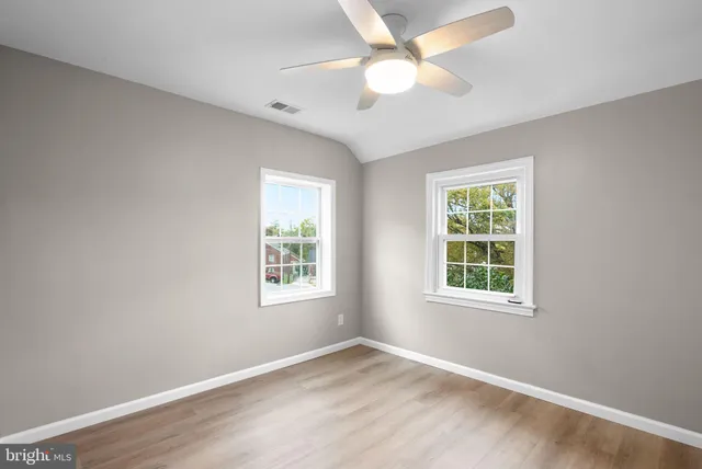 an empty room with a window and a fan