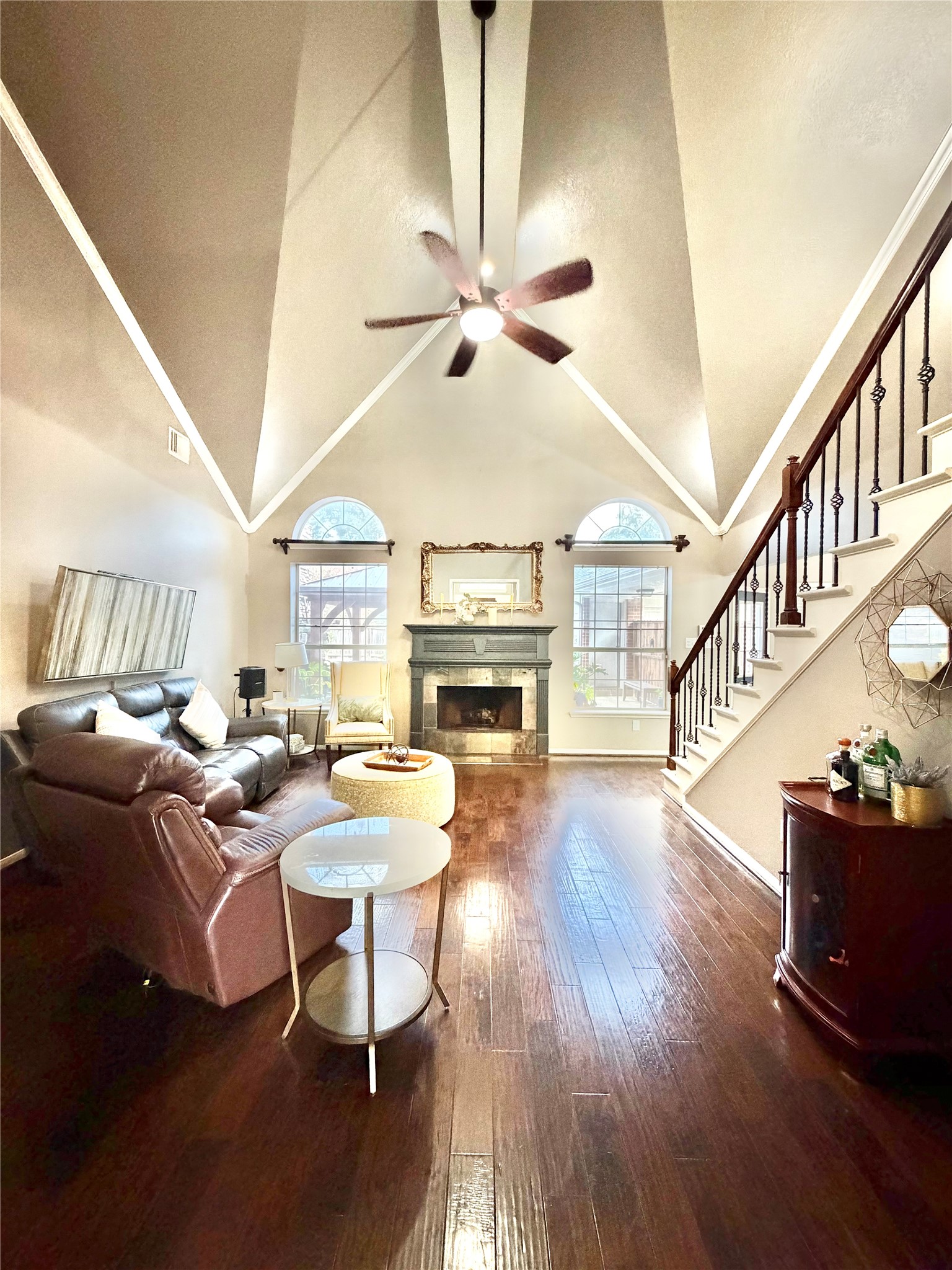 20110 Forest Drive Spring, TX 77388 - Photo 8 of 43 Spacious living room with vaulted ceilings, elegant fireplace, and abundant natural light, complemented by a stylish staircase and warm hardwood floors.