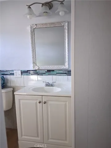 a bathroom with a granite countertop sink a toilet and a mirror